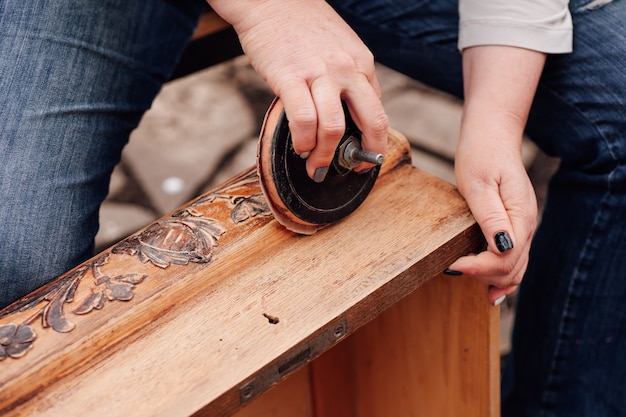 Macro womens hands sand an old wooden box with a floral pattern removing the old polish and preparin...