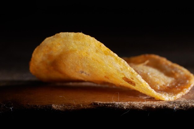 Macrofoto van chips op een houten tafel, een plakje gebakken aardappelen, biersnacks, wazige achtergrond