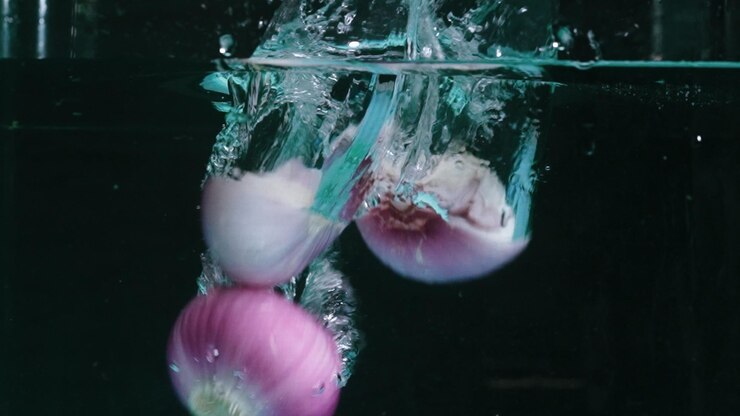 Photo macrography of fresh red onions dropping into water with splash water pabulum
