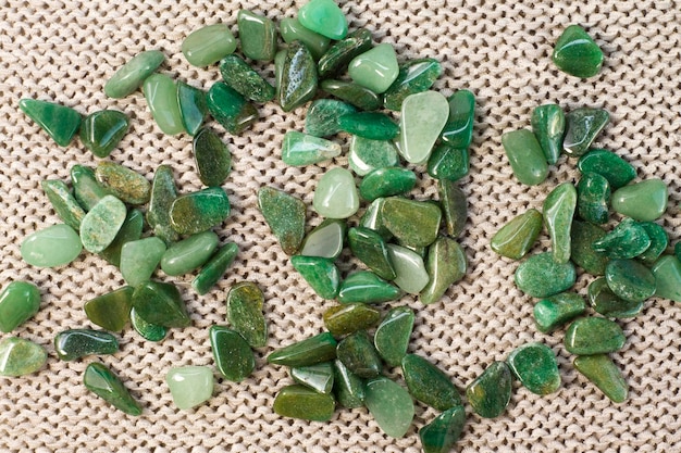 Macroshooting of natural mineral rock specimen tumbled green aventurine gemstone on beige background