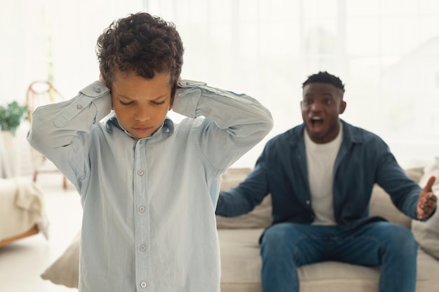 Photo mad african american dad shouting at scared kid son indoor