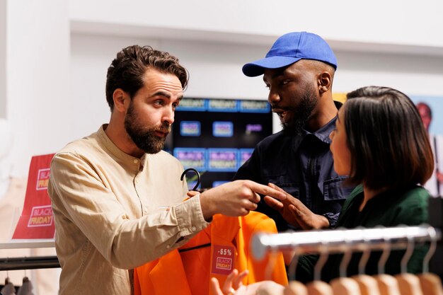 Mad gekke klanten man en vrouw vechten over koopjes in een winkelcentrum. Afro-Amerikaanse man beveiligingsagent die te maken heeft met boze agressieve shoppers in een kledingwinkel tijdens Black Friday verkopen