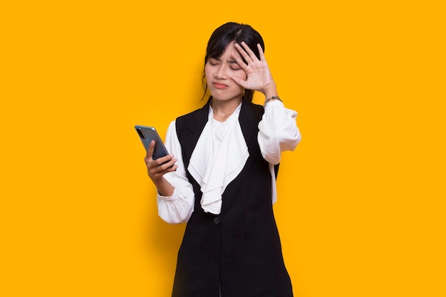сумасшедшая и шокирующая молодая азиатская красивая женщина с помощью мобильного телефона на желтом фоне