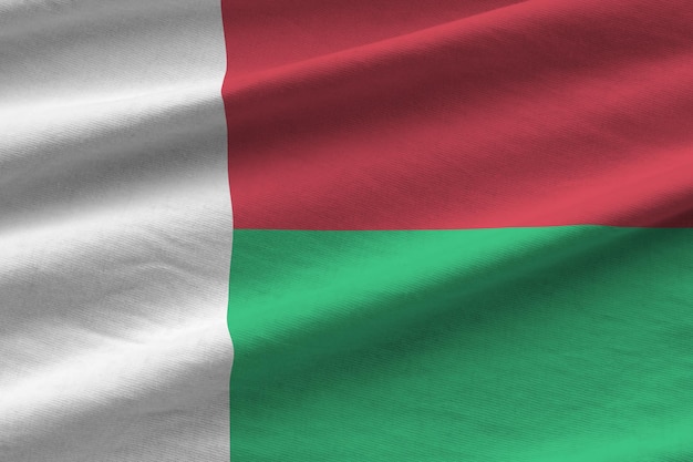 Madagascar flag with big folds waving close up under the studio light indoors The official symbols and colors in banner