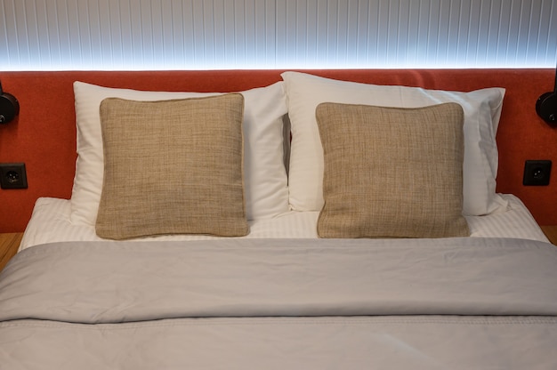 침대와 갈색 베개를 만들었습니다. 호텔 방에서 만든 침대의 클로즈업. 방에 깨끗한 침구, 베개, 침대 시트 및 담요. 인테리어 디자인의 클로즈업입니다.