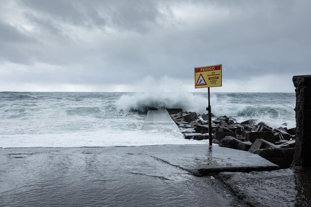 Foto madeira portugal waarschuwingsbord in een jachthaven op een stormachtige dag met grote golven die de kust raken