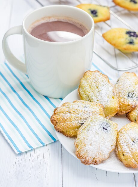 Madeleines in poedervorm met bosbessen en warme chocolademelk