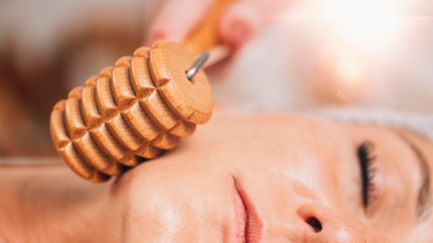 Maderotherapie gezichtsmassage met houten roller die rimpels en slappe wangen vermindert