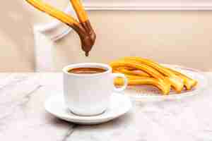 Photo madrilenian breakfast churro dipped in hot milk chocolate on white marble table