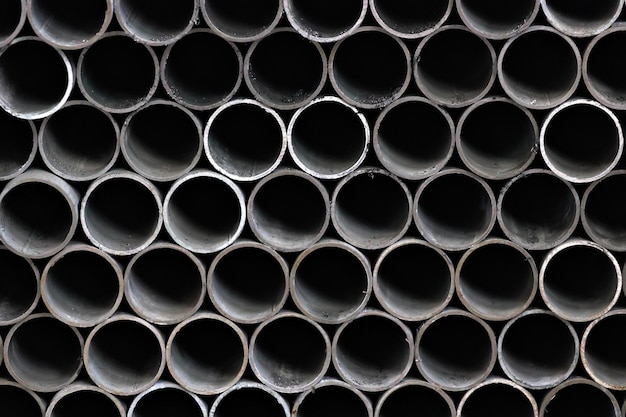 Maetallic pipes of the same diameter are neatly stacked View of pipes from the front Background