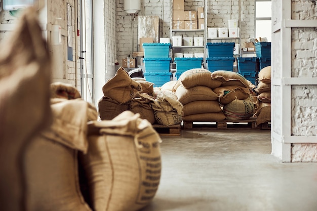 Magazijn met koffiebonen verpakt in jutezakken en blauwe containers