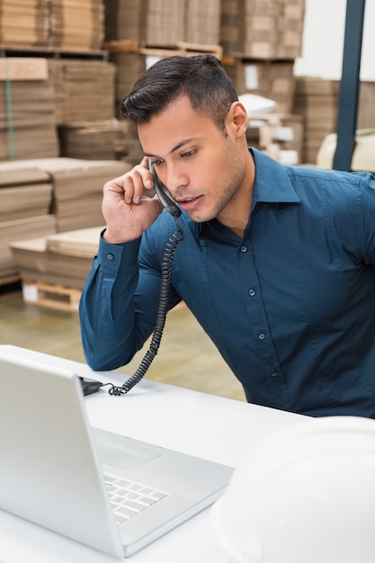 Magazijnbeheerder met telefoon en laptop