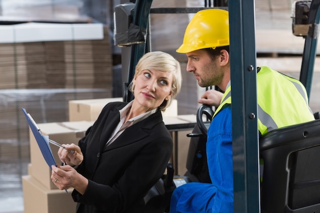 Foto magazijnmanager die met heftruckbestuurder spreekt