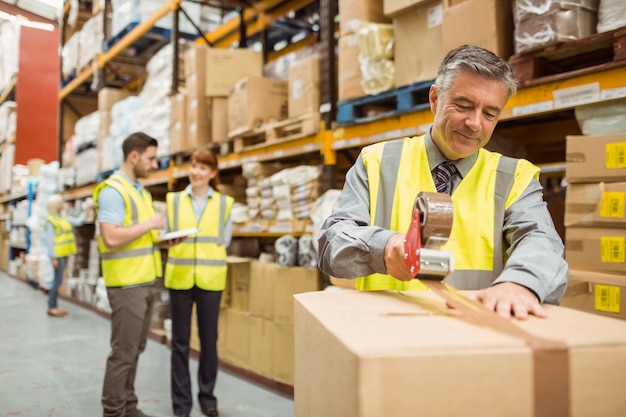 Magazijnmedewerker die kartonnen dozen verzegelt voor verzending