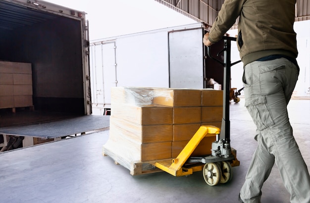 Foto magazijnmedewerker lossen palletzending goederen in een vrachtwagen. levering en transport van vrachtvracht.