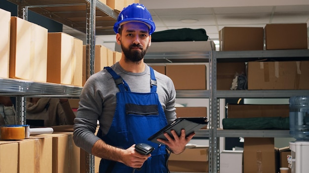 Magazijnmedewerker scant streepjescodes op dozen, controleert vracht voor distributie of verzending. Jonge man aan het werk met scanner en digitale tablet in magazijn, industriële goederen verzenden.