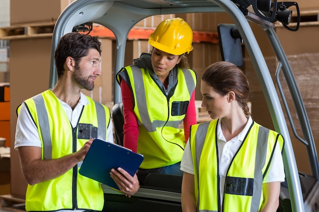 Magazijnmedewerkers praten met heftruckchauffeur