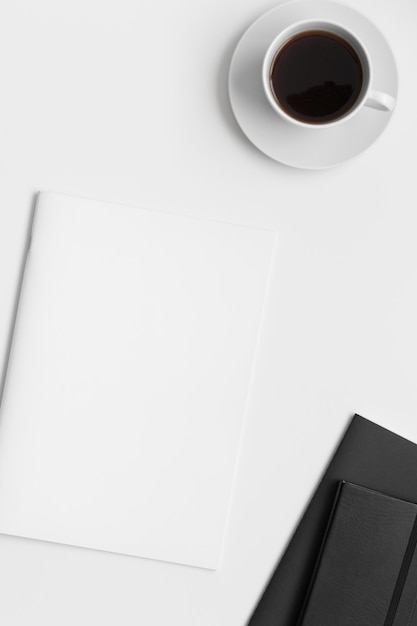 Magazine mockup with a cup of coffee and workspace accessories\
on the white desk