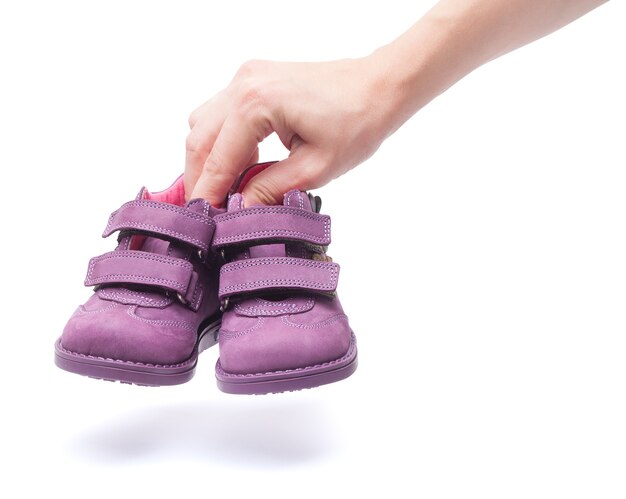 Magenta children`s boots on female hand. isolated
