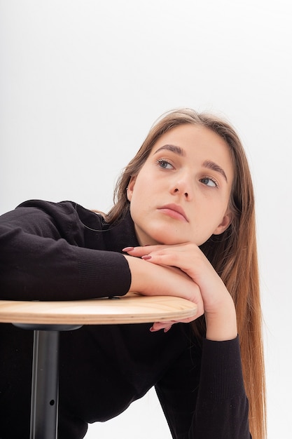 Magere blanke mooie vrouw in zwarte coltrui, spijkerbroek leunt op kruk