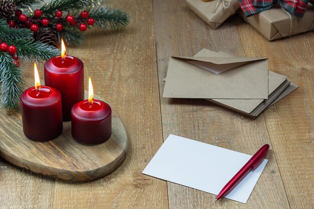 Foto magic christmas tre candele accese rosse accanto a una lettera, un albero di natale e regali