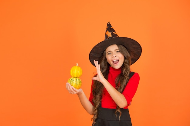 Magic kid cast spell on pumpkin child celebrate autumn holiday teenage girl in witch hat celebrate halloween happy halloween trick or treat concept carnival festive costume of witch