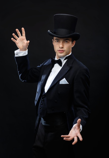 magic, performance, circus, show concept - magician in top hat showing trick