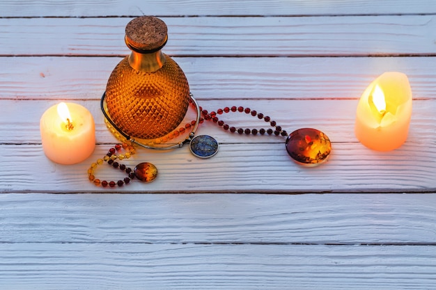 Magic potion and amber necklace on blue wooden background