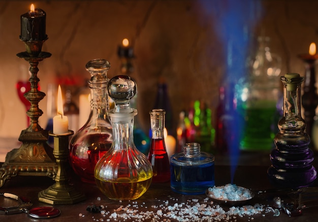 Magic potion, ancient books and candles on dark background