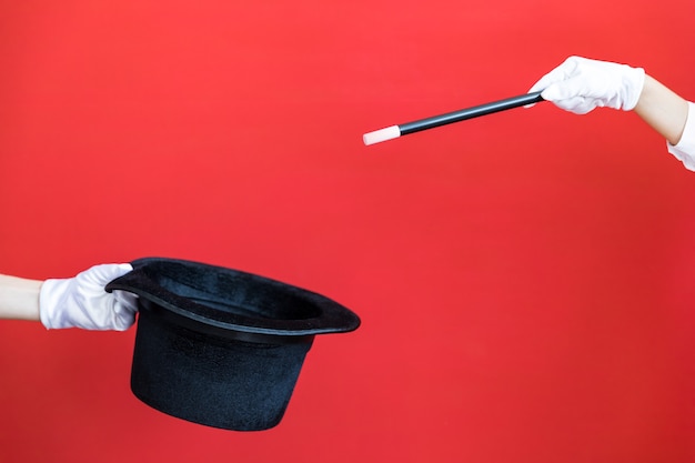 Magic wand and black top hat against red wall