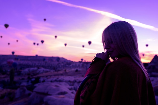 Alba magica a goreme cappadocia turchia. una ragazza in un canyon in abiti tradizionali circondata da palloncini sotto i raggi del sole nascente