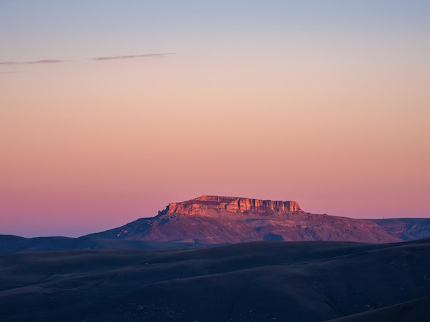 Волшебный пурпурный рассвет над плато Бермамыт Атмосферный пейзаж рассвета с красивым плато Бермамыт вдалеке