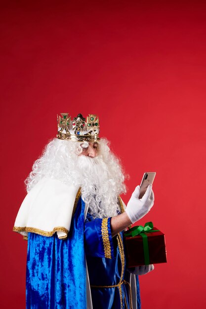 Magician King using a mobile phone on red background