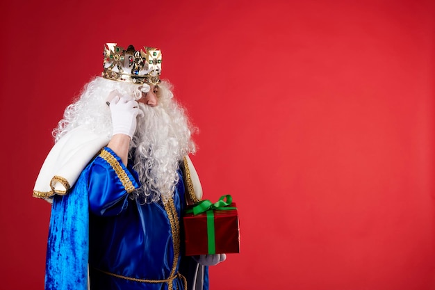 Magician King using a mobile phone on red background