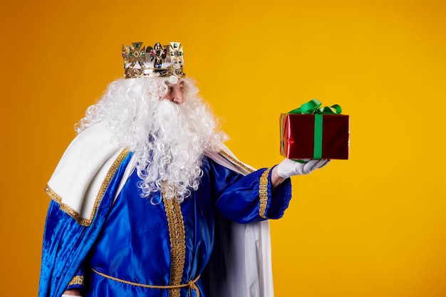 The Magician King with a present on a yellow background