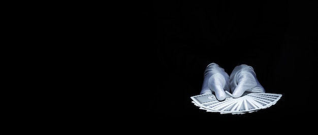 Photo magician's hand showing fanned deck of playing card against black background