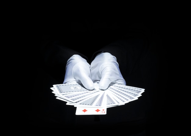 Magician's hand showing fanned deck of playing card against black background