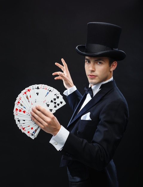 magie, prestatie, circus, gokken, casino, poker, showconcept - goochelaar in hoge hoed die truc met speelkaarten toont