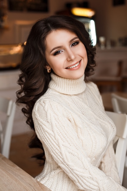 Magische verbazingwekkende schoonheid van een jonge vrouw die in café zit. Brunette dromen. Mooi golvend haar, luxe make-up.