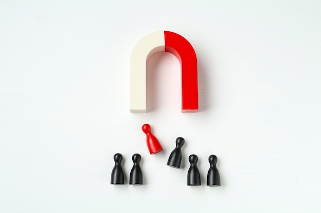 Magnet attracting colorful game pieces on white background flat lay