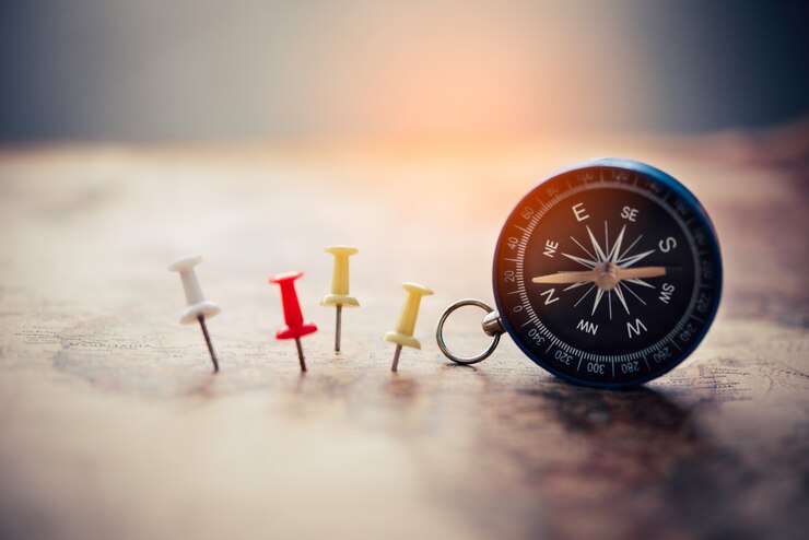 Magnetic compass and embroidery needle is on the map. on a world map conceptual of global travel 