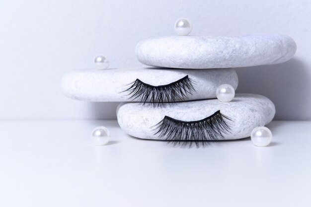 Magnetic fake artificial eyelashes and pearl on white stones.