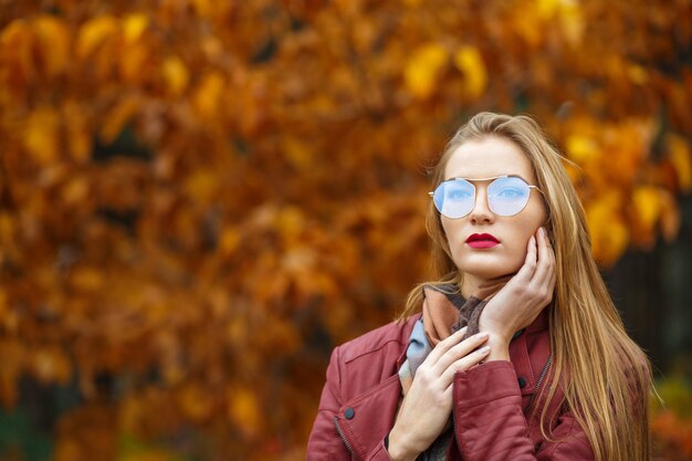 Foto magnifica donna bionda dai capelli lunghi che indossa giacca rossa e occhiali. spazio vuoto