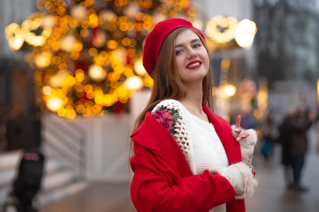 Magnificent young woman in red coat walking at the street fair. Empty space