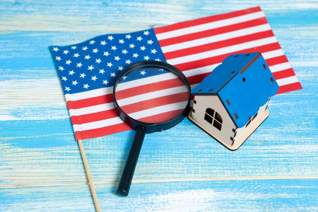 Magnifier, American flag and house. home search concept. home inspection on a blue table