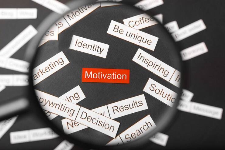Magnifier glass over the red inscription motivation cut out of paper,