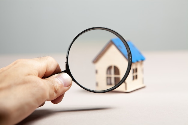 Magnifier and house on a pink background. home search concept