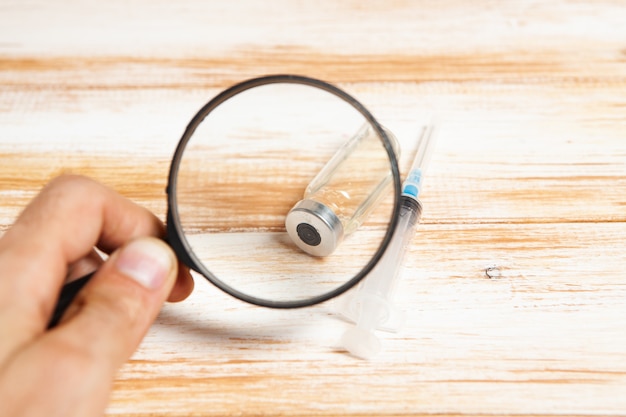 Magnifier, vial and syringe on the table