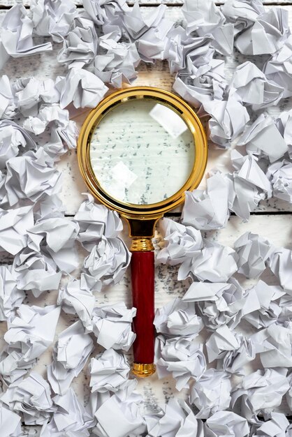 Magnifier with important message with paper wraps around on floor magnifying glass with crutial data with crumpled notes all over optical instrument showing new ideas