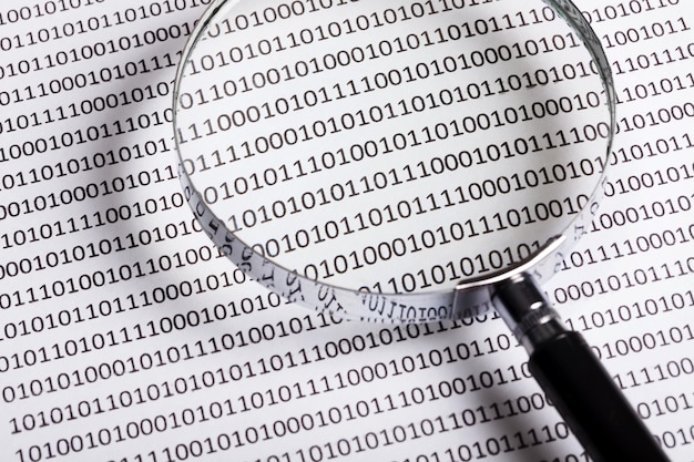 Photo magnifying glass on the background of a binary code